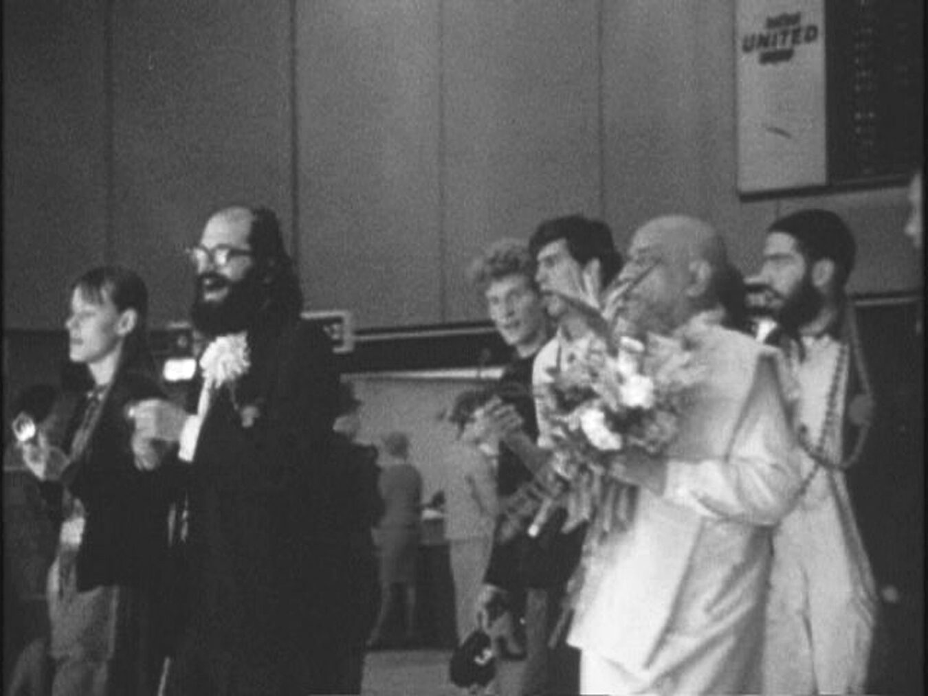 Allen Ginsberg greets Srila Prabhupada on his arrival at San Francisco airport, 17 January 1967, alongside early disciples Shyamasundara Dasa and Ranchor Dasa.